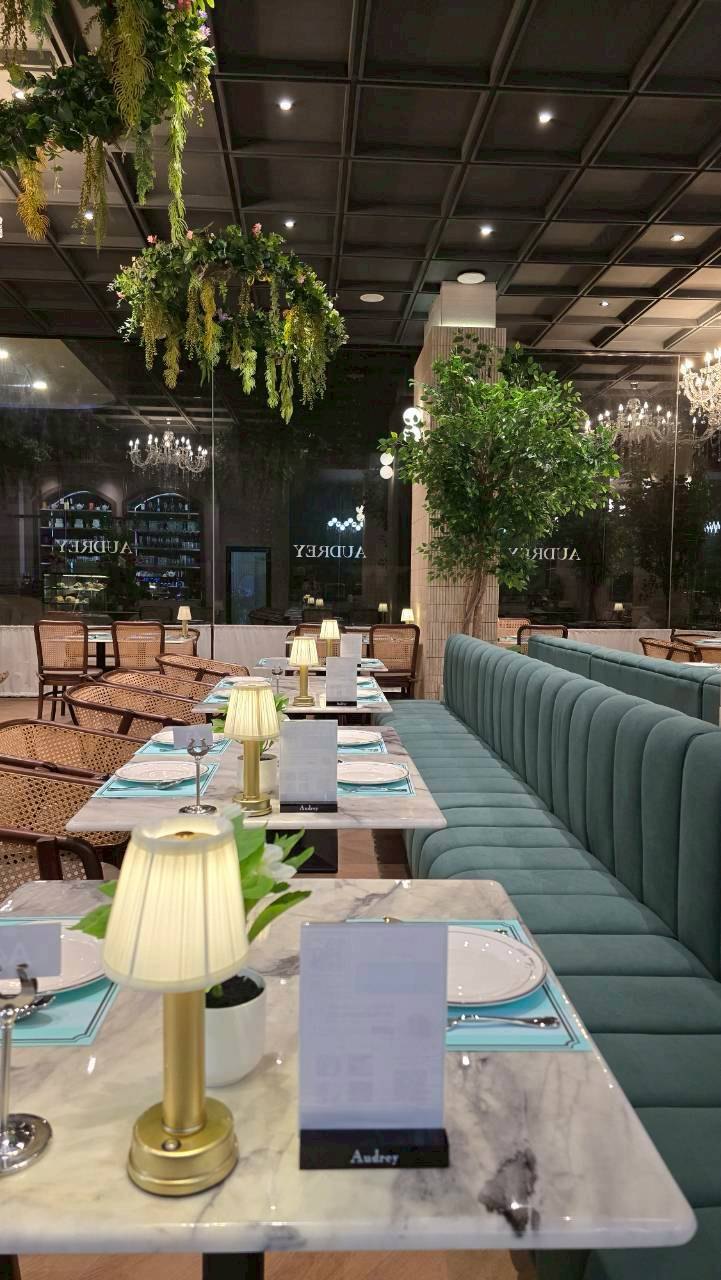 ภายในห้องอาหาร Audrey Cafe ที่ Milton Hotel Buriram โซฟาเบาะกำมะหยี่สีเขียวและโต๊ะหินอ่อน